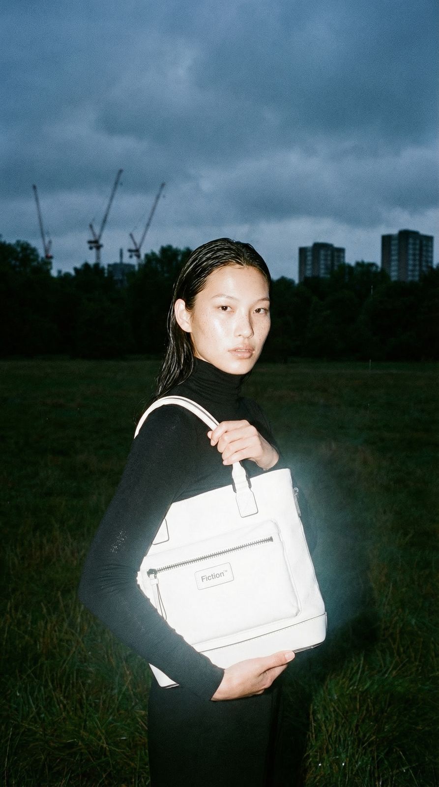 a woman standing in a field holding a white bag