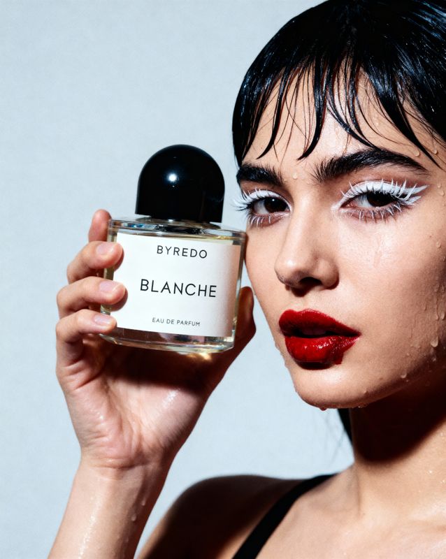 a woman holding a bottle of perfume in front of her face