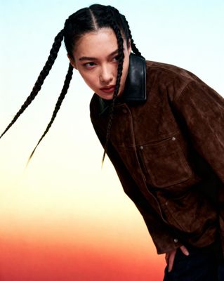 a woman with braids standing in front of a sunset