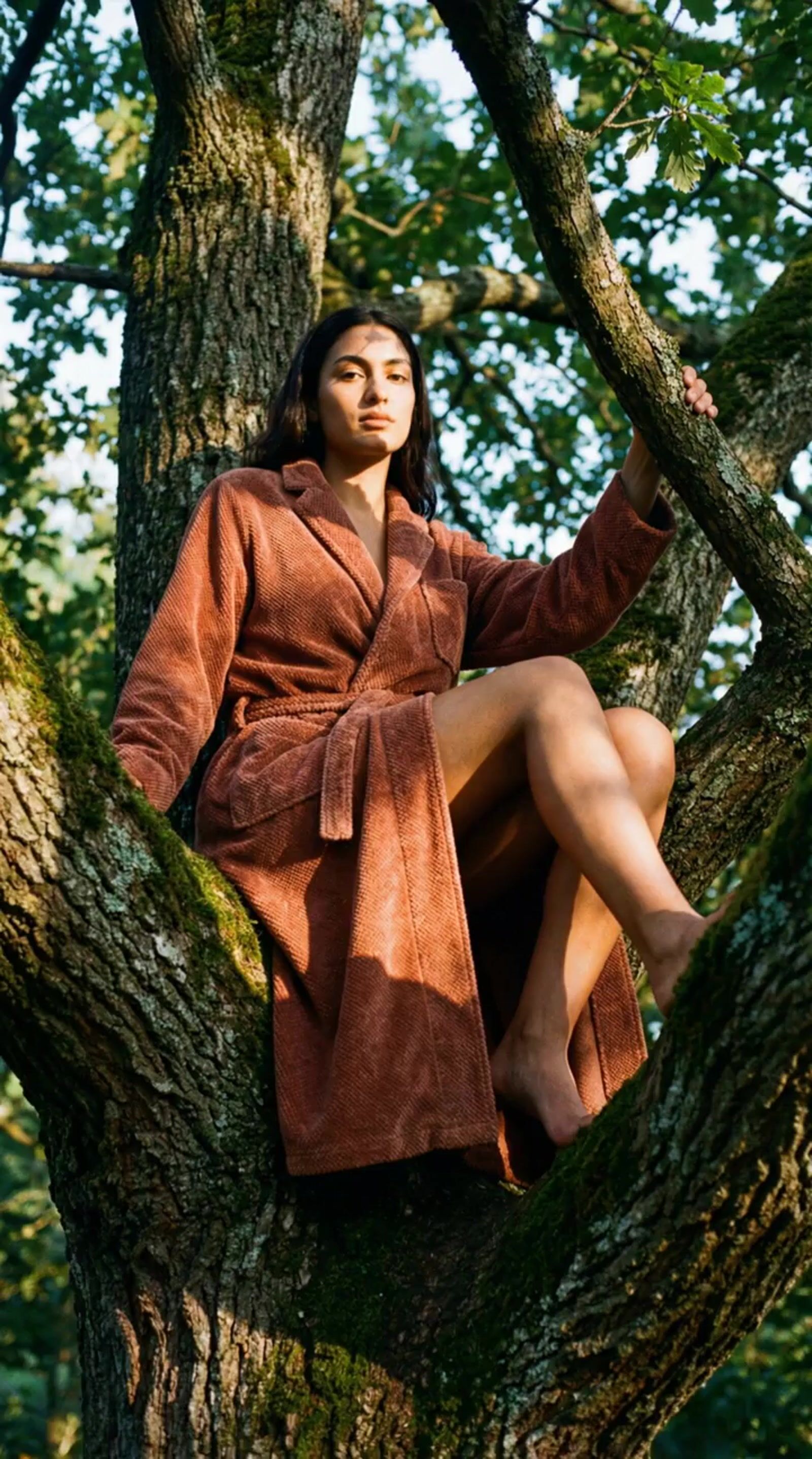 a woman sitting in a tree wearing a robe