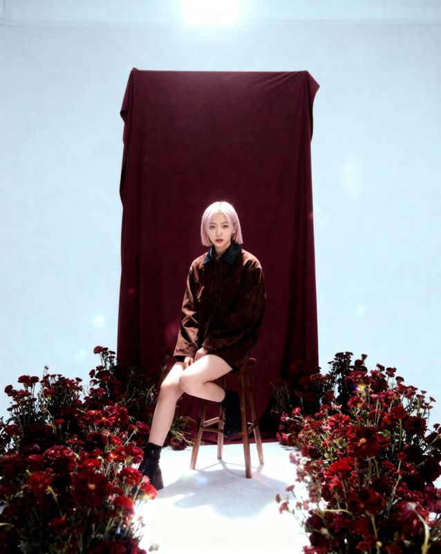 a woman sitting on a chair in front of flowers