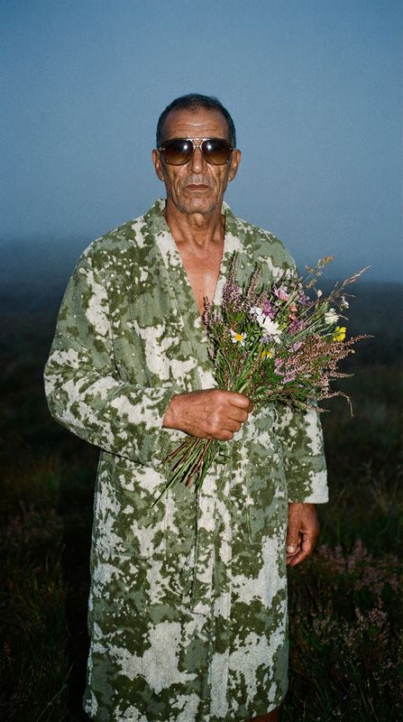 a man in a bathrobe holding a bouquet of flowers