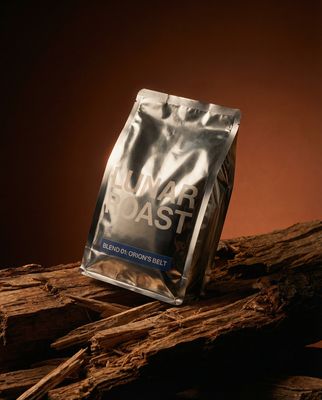 a bag of roast sitting on top of a pile of wood