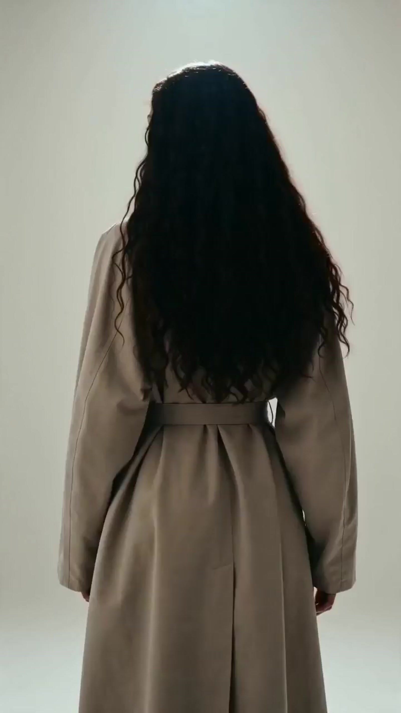 the back of a woman's coat with long curly hair