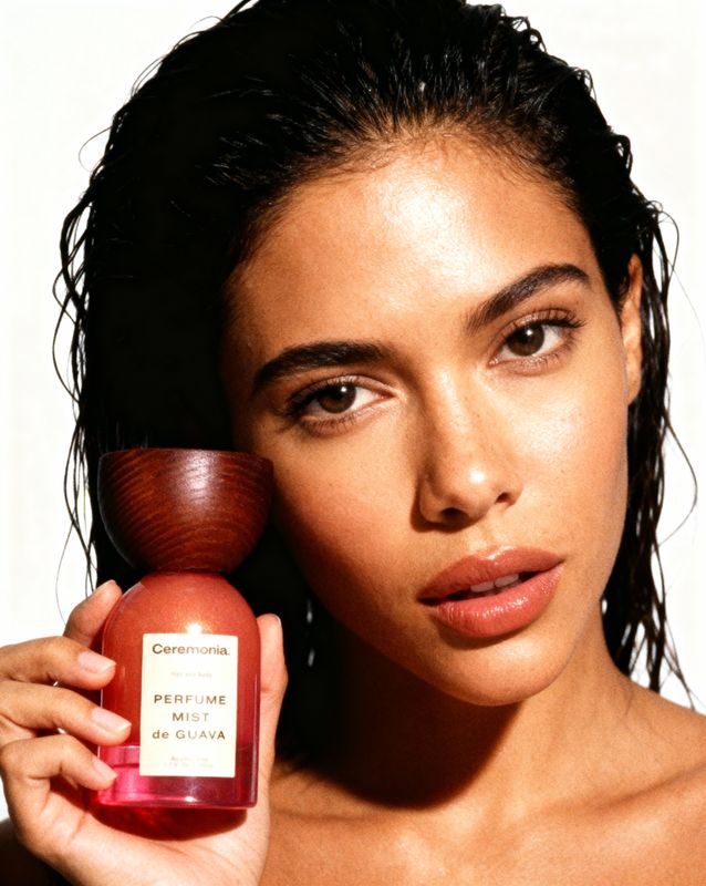 a woman holding a bottle of perfume next to her face