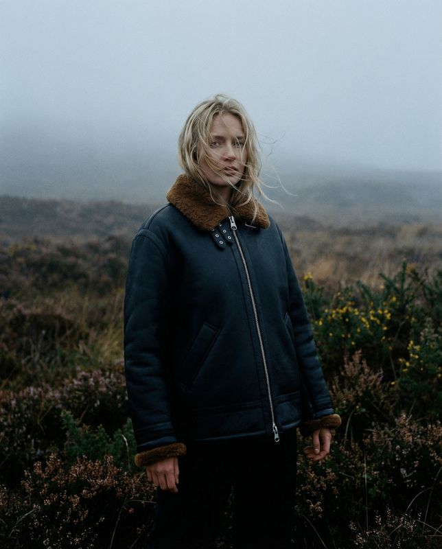 a woman standing in a field on a foggy day