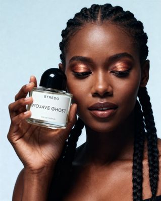 a woman with braids holding a bottle of perfume