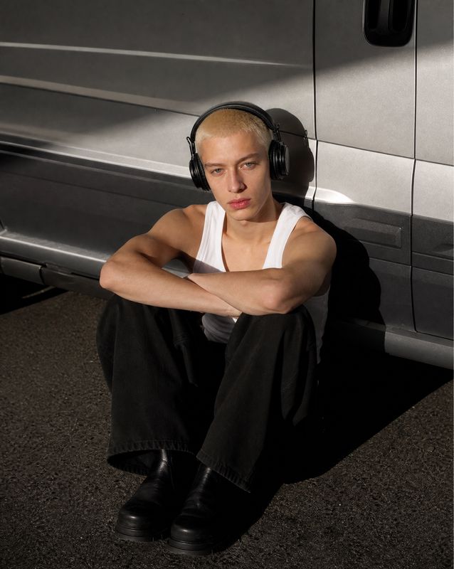a man with headphones sitting in front of a van