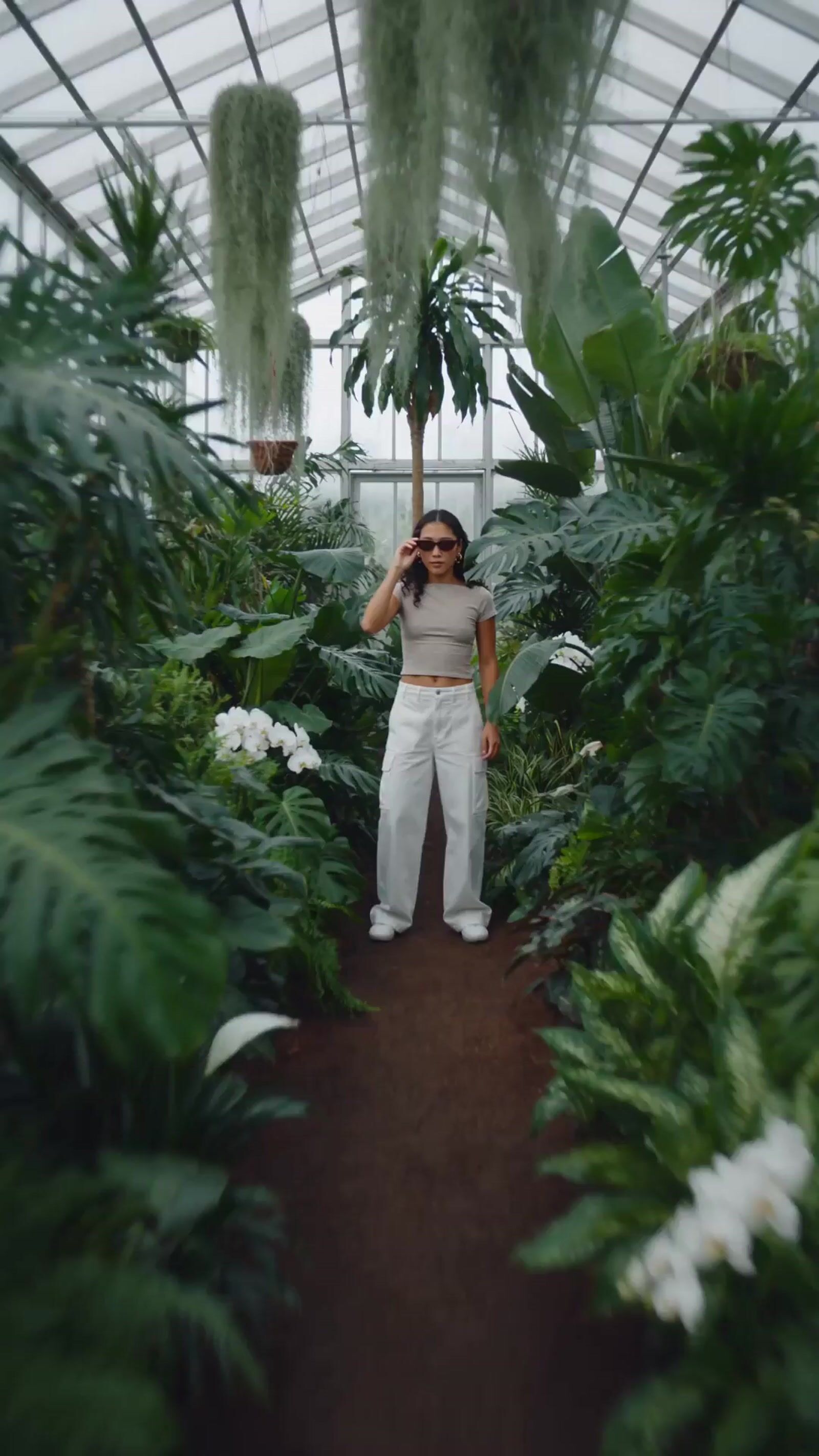 a woman standing in a greenhouse talking on a cell phone