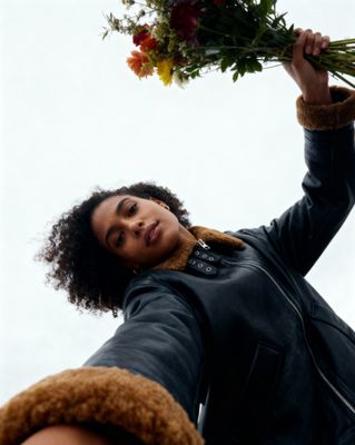a woman holding a bunch of flowers up in the air