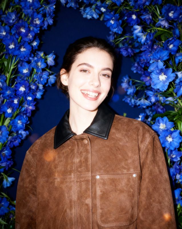 a woman standing in front of blue flowers