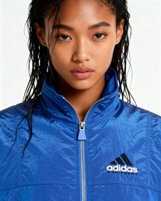 a young woman wearing a blue adidas jacket