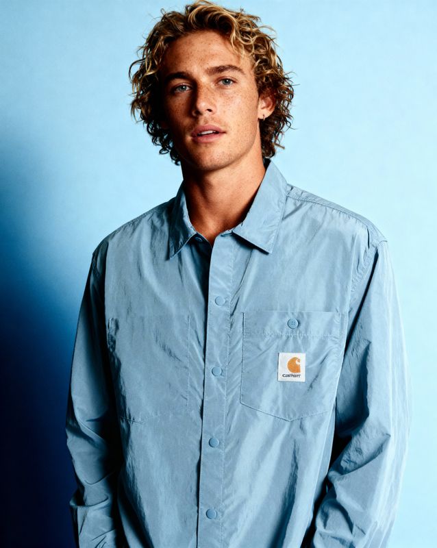 a man with curly hair wearing a blue shirt