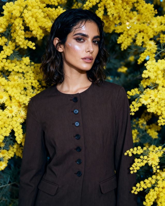 a woman standing in front of yellow flowers