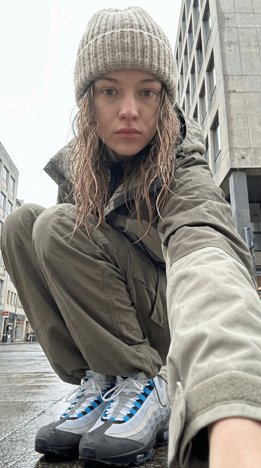 a woman sitting on the ground in the rain