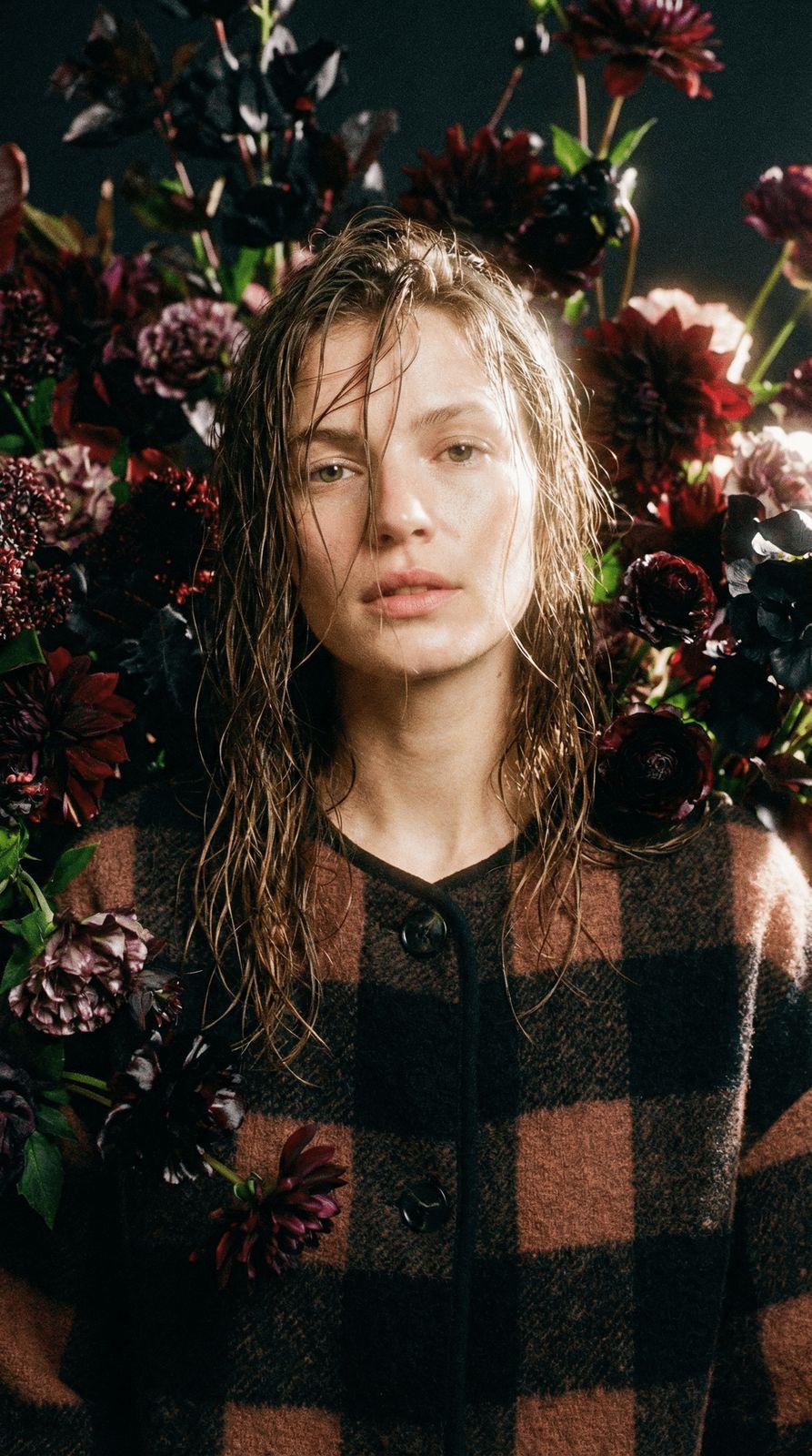 a woman standing in front of a bunch of flowers