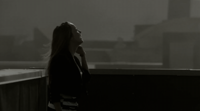 a woman standing on a balcony talking on a cell phone