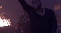a man standing in front of a fire with his arms in the air