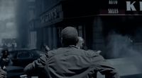 a man in a trench coat walking down a street