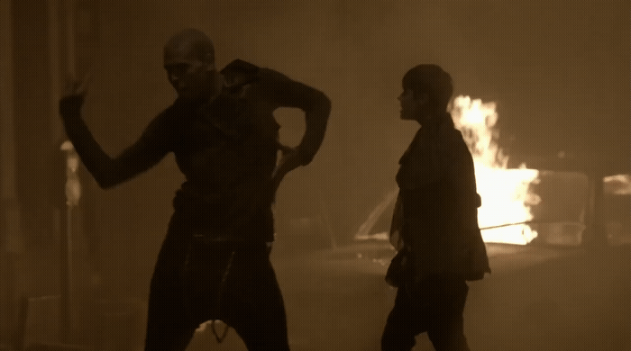 a couple of people standing in front of a fire