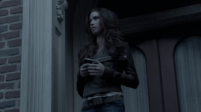 a woman standing outside of a building looking at her cell phone