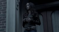 a woman standing outside of a building looking at her cell phone
