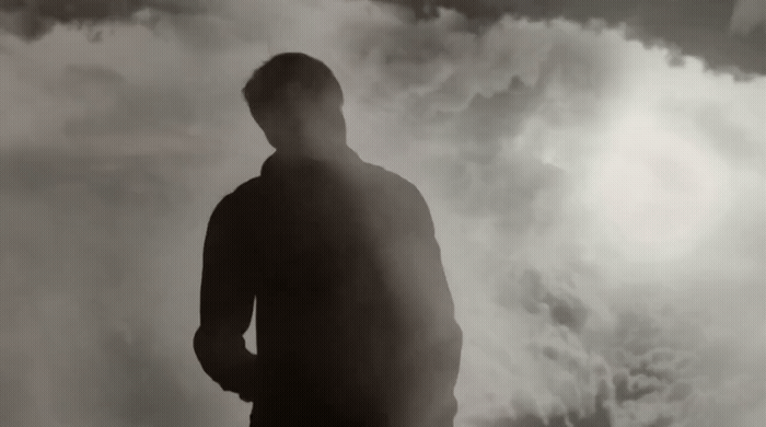 a man standing in front of a cloudy sky