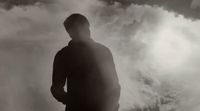 a man standing in front of a cloudy sky