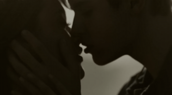 a black and white photo of a man kissing a woman