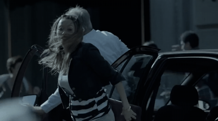 a woman walking out of a car with a man in the background