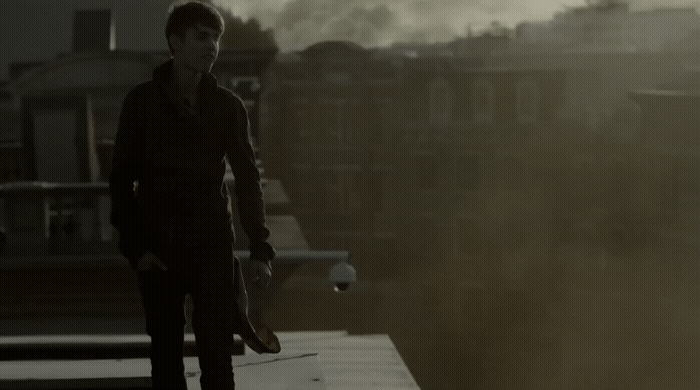 a man standing on top of a roof next to a tall building