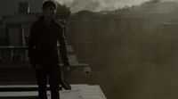 a man standing on top of a roof next to a tall building