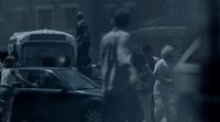 a group of people standing around a car in the rain