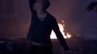 a man standing in front of a fire with his arms in the air