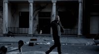 a man walking across a street in front of a building