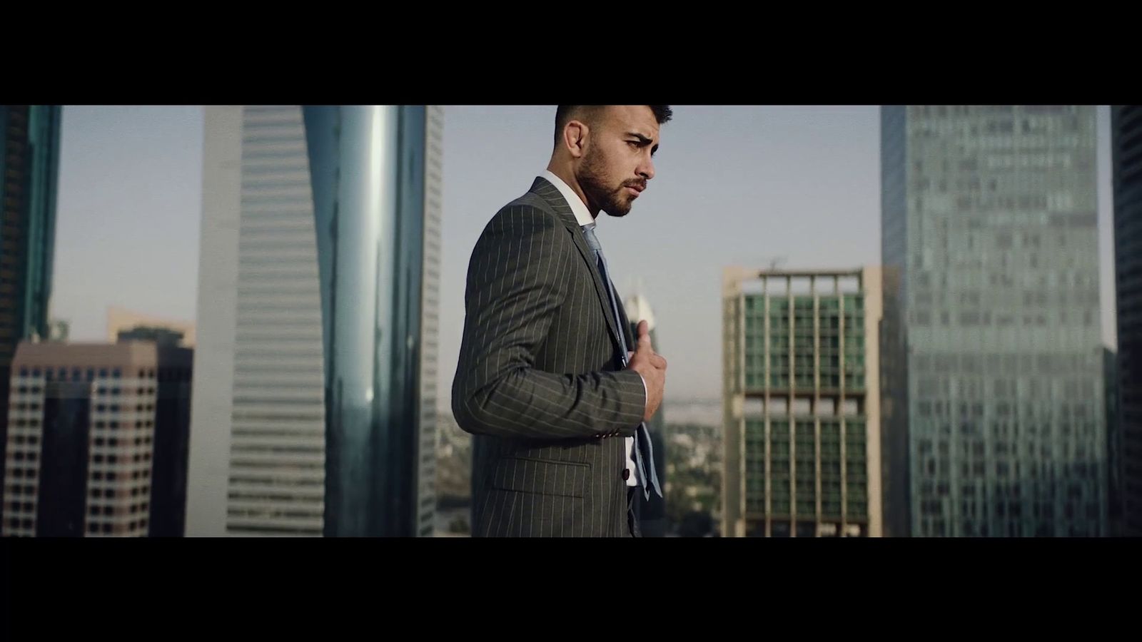 a man in a suit and tie standing in front of tall buildings