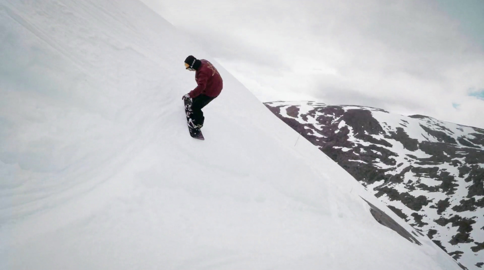 a man riding a snowboard down the side of a snow covered slope