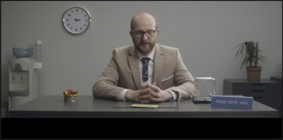 a man sitting at a desk with a clock in the background