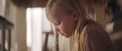 a little girl sitting at a table with a plate of food