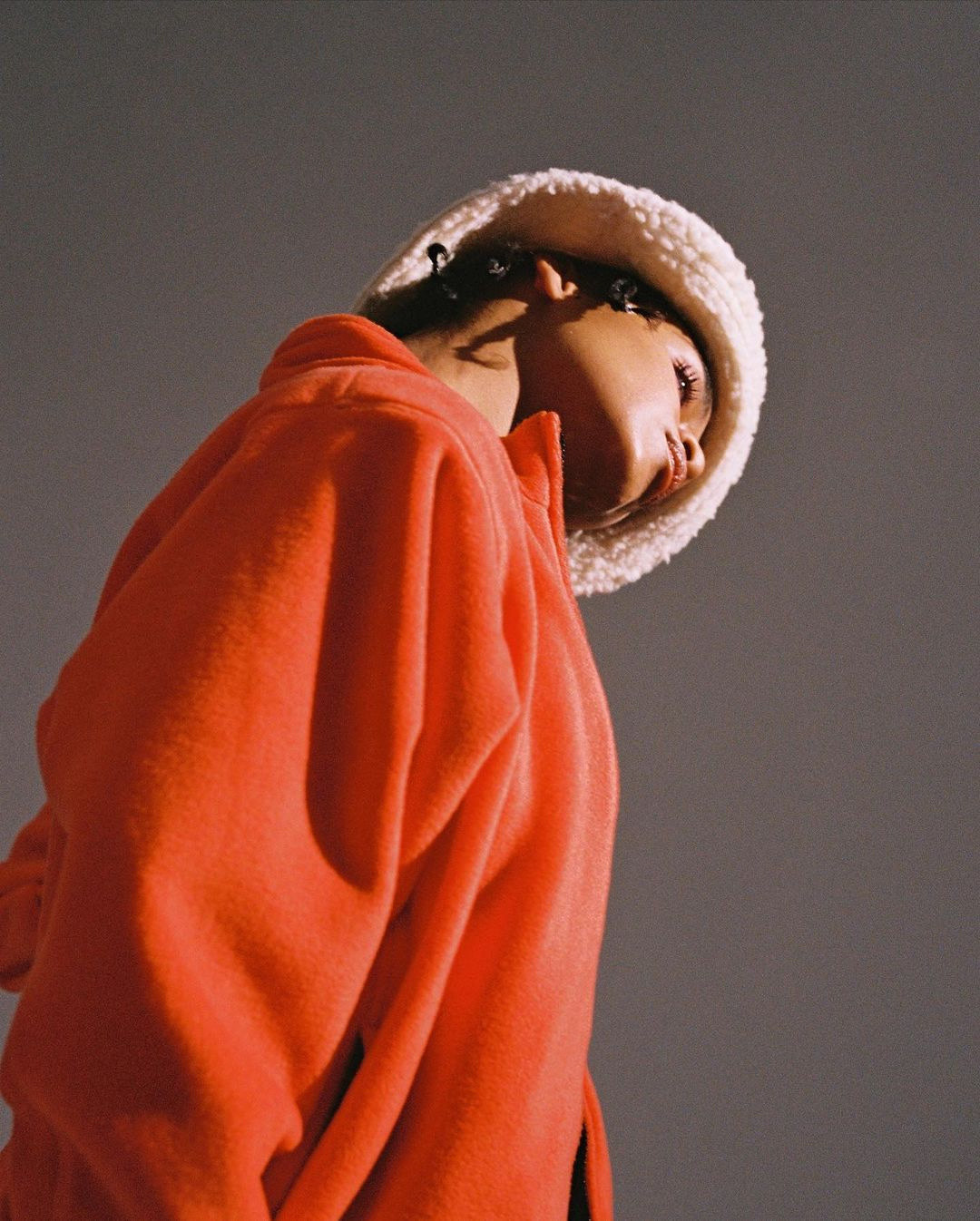 a woman in an orange sweatshirt and a white hat