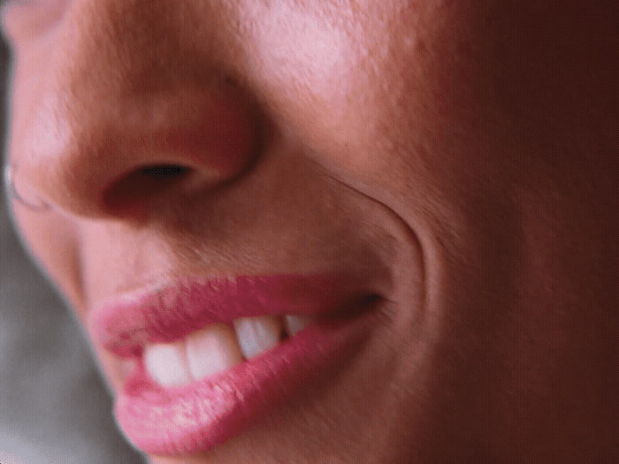 a close up of a woman's face with a toothbrush in her mouth