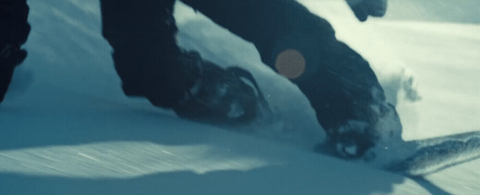 a person riding a snowboard down a snow covered slope