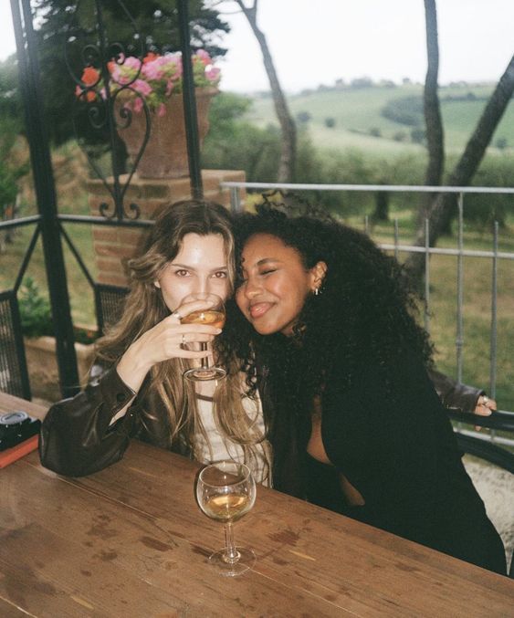 two women sitting at a table drinking wine