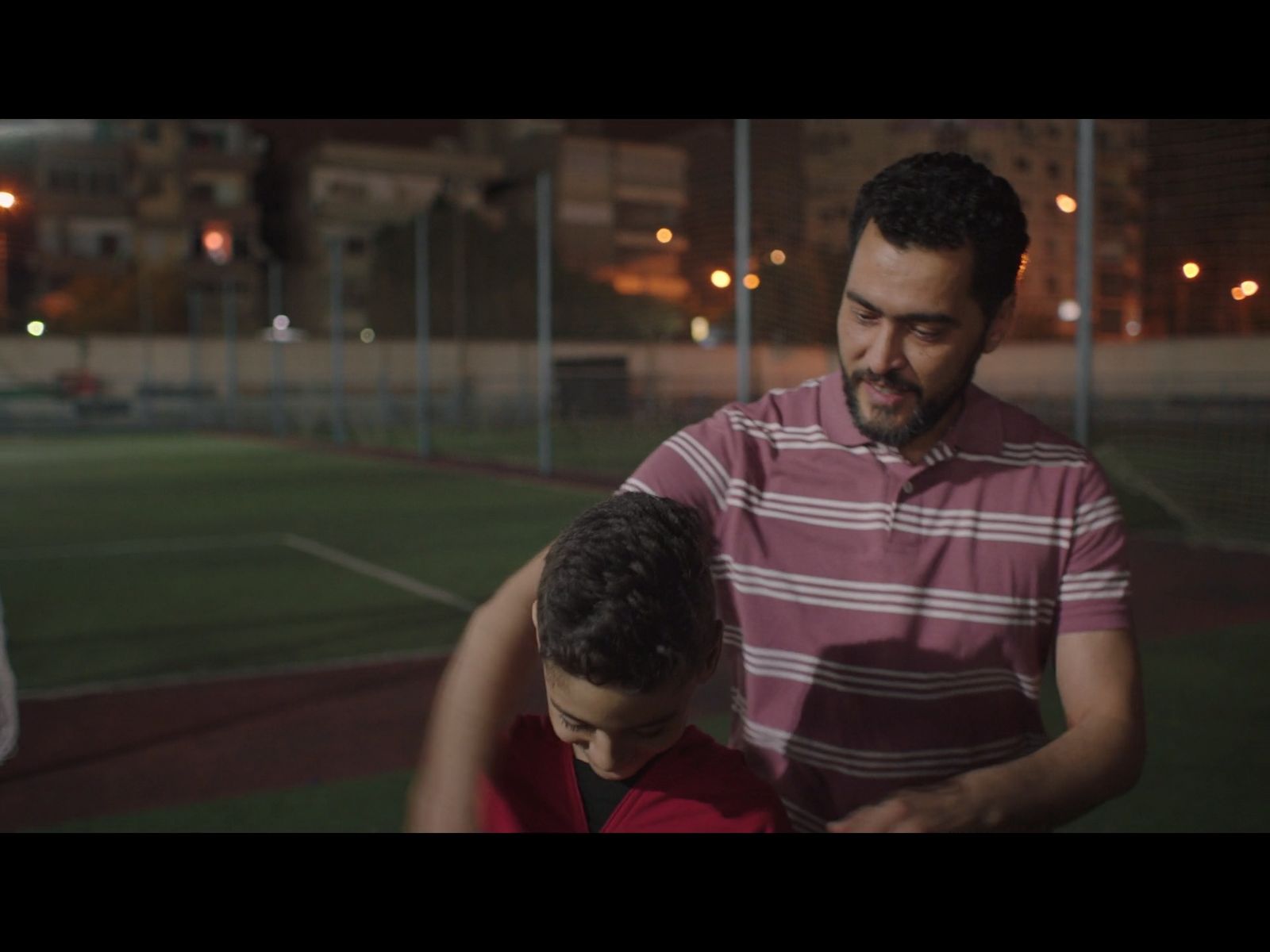 a man standing next to a little boy on a tennis court