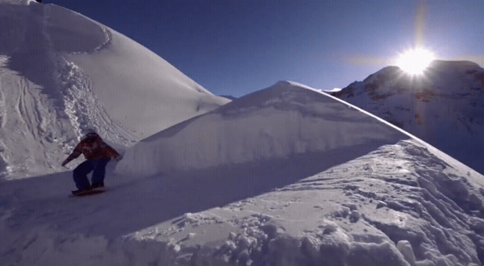 a man riding a snowboard down the side of a snow covered slope