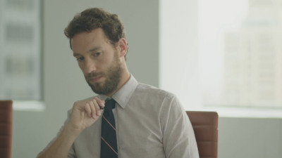 a man in a dress shirt and tie sitting at a desk