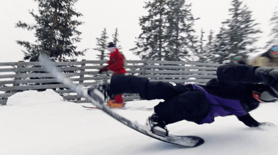 a man riding a snowboard down the side of a snow covered slope