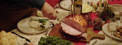 a person cutting a ham on a cutting board