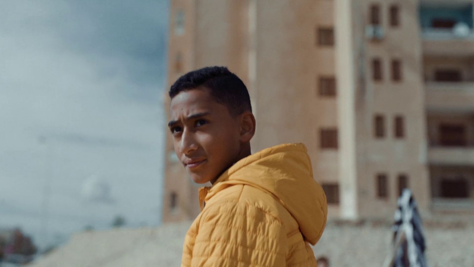 a man in a yellow jacket standing in front of a tall building