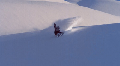 a man riding a snowboard down a snow covered slope